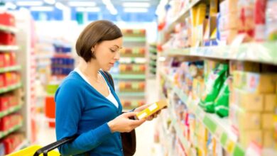 donna al supermercato che legge un'etichetta sulla confezione di un alimento per controllare i livelli di sale presente