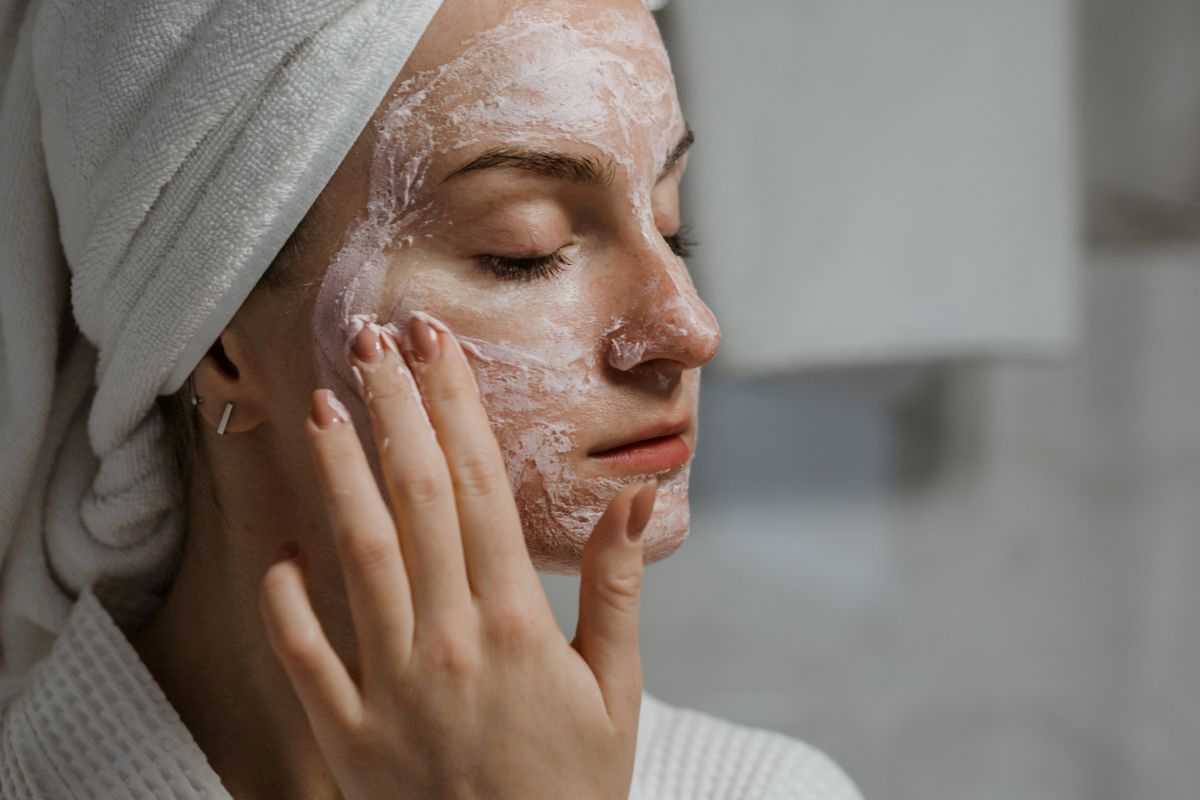ragazza che fa lo scrub sulla pelle del viso