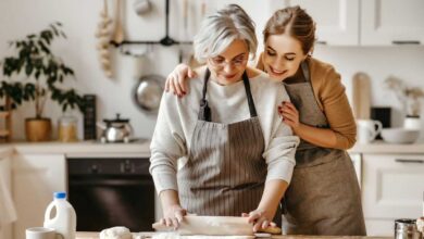 donna anziana che cucina mentre la figlia la abbraccia