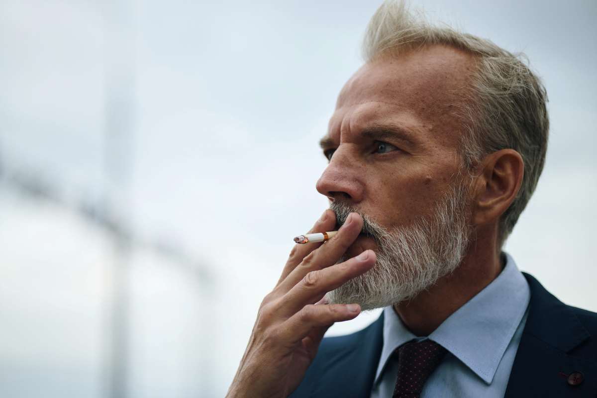 un uomo maturo fuma una sigaretta
