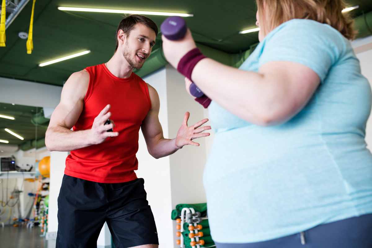 una donna obesa fa sport seguita da un personal trainer