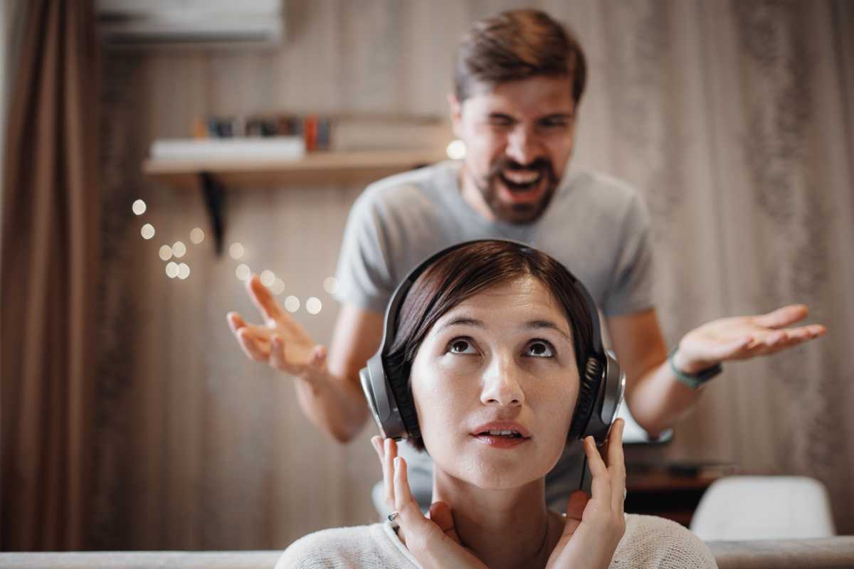 una ragazza ascolta la musica con le cuffie mentre il fidanzato grida alle spalle