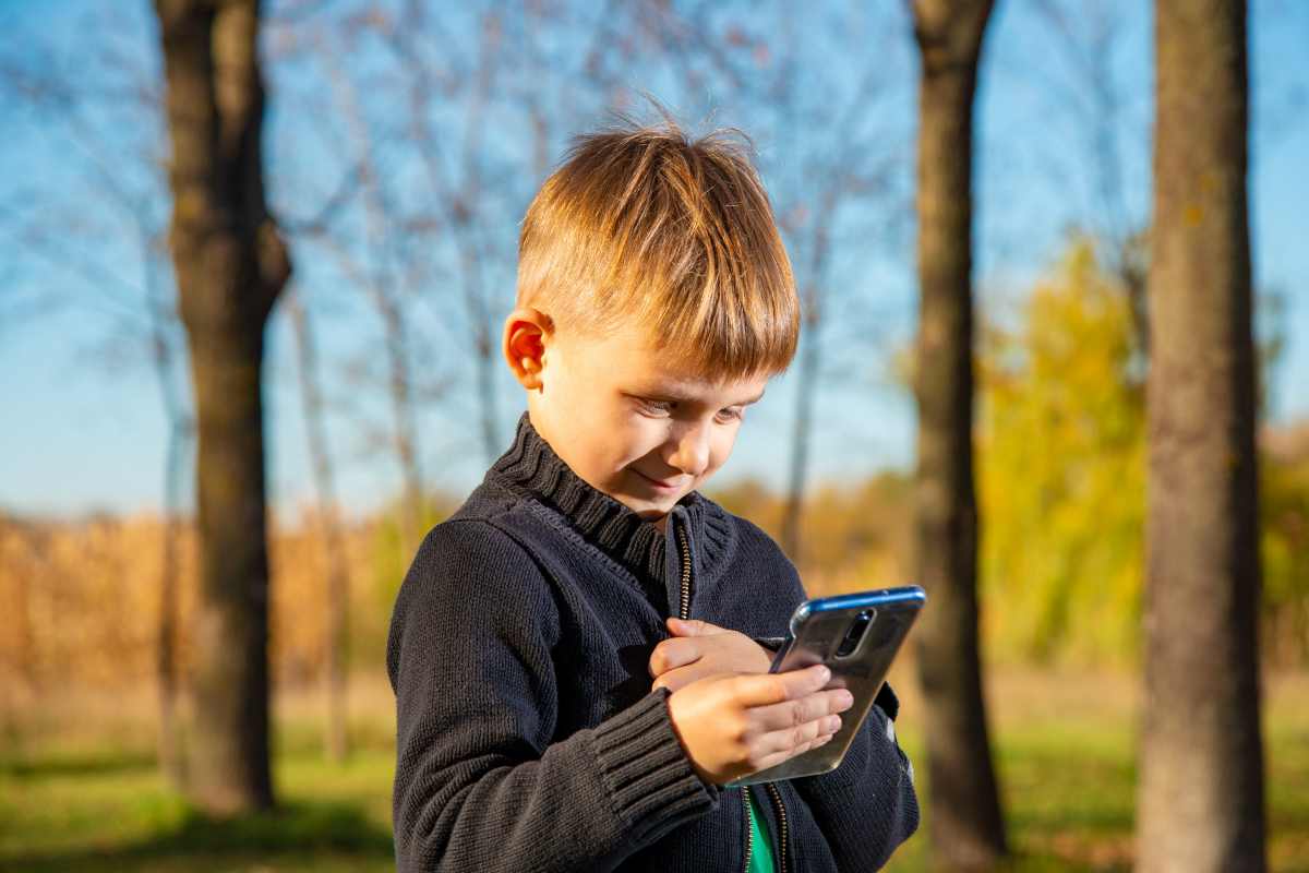 un ragazzino guarda il suo smartphone piegando il collo in avanti