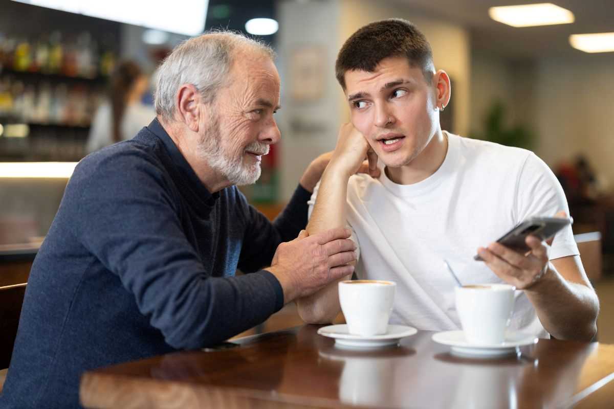 ragazzo giovane che cerca di spiegare funzionamento dello smartphone a una persona anziana facendo ageismo