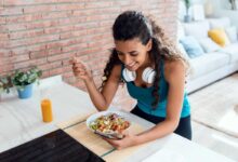 alimentazione e sport: donna sportiva seduta al tavolo della cucina mentre mangia un piatto sano