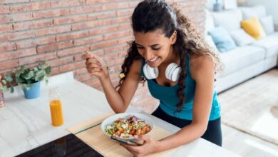 alimentazione e sport: donna sportiva seduta al tavolo della cucina mentre mangia un piatto sano