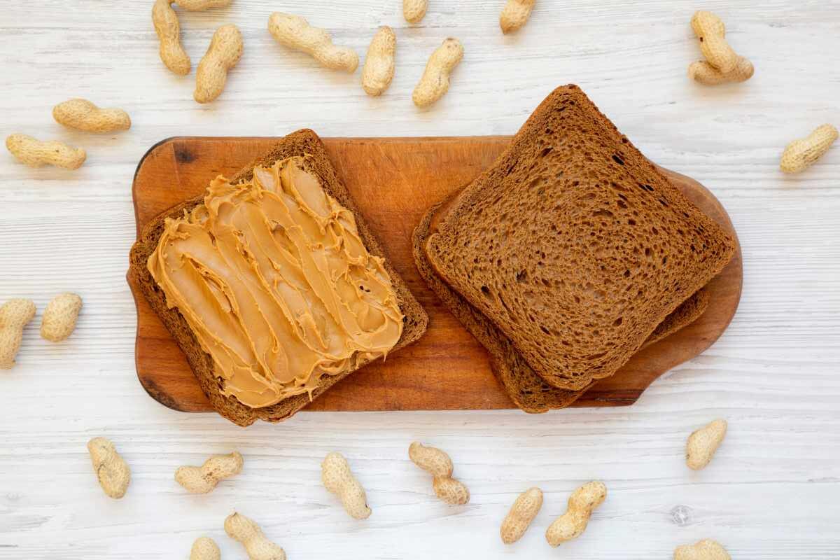 pane integrale con burro di arachidi circondato da noccioline