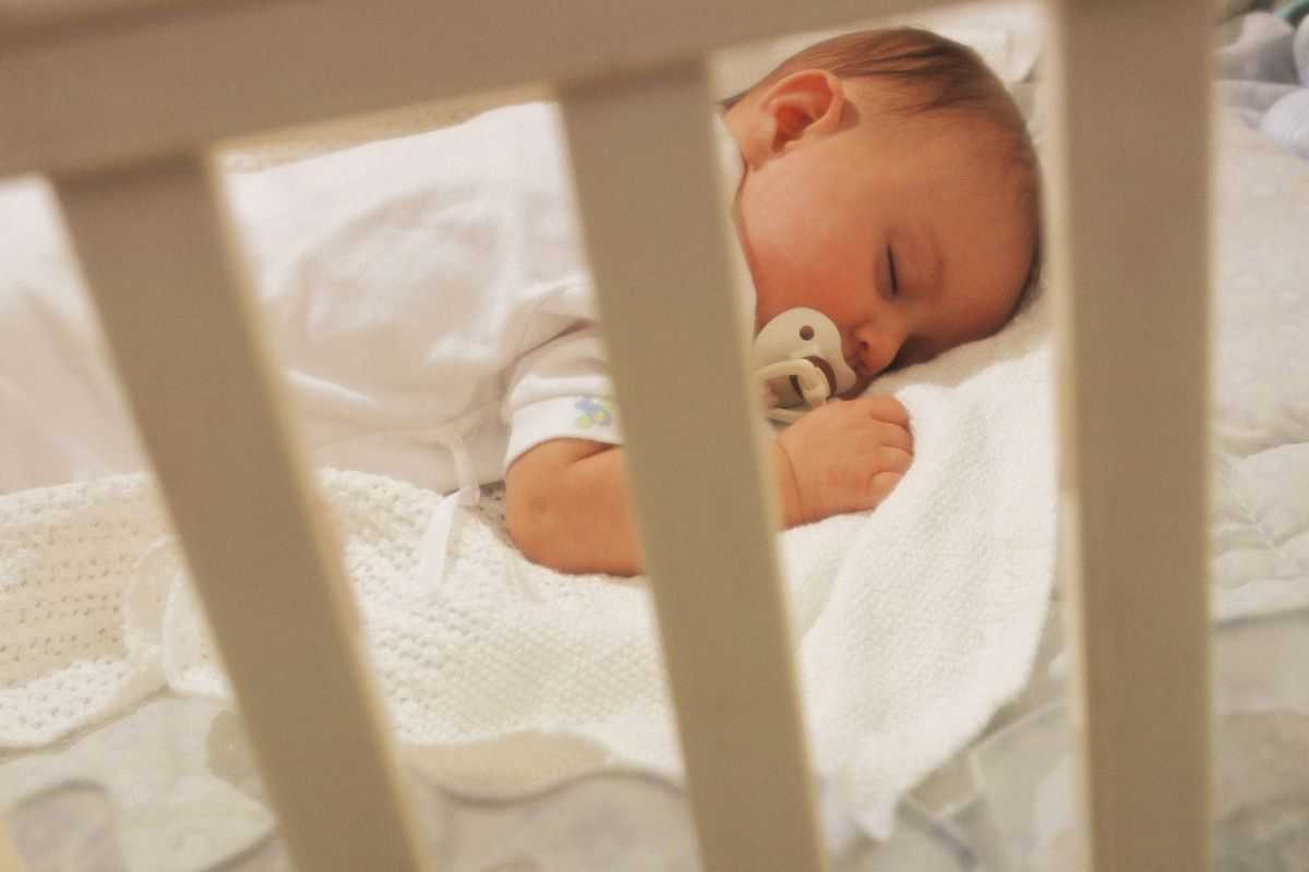 bambino che dorme nella culla con il ciuccio