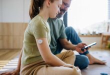 bambina con sensore per il diabete con affianco il papà che le fa vedere l'app sullo smartphone