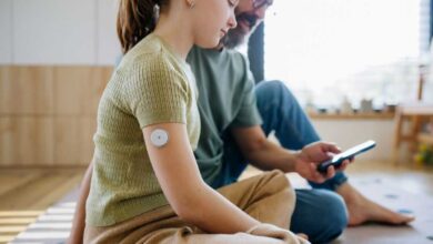 bambina con sensore per il diabete con affianco il papà che le fa vedere l'app sullo smartphone