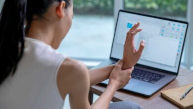 donna con dolore e formicolio alla mano al computer