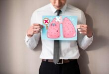 un uomo mostra un foglio con il disegno dei suoi polmoni malati