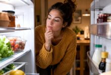 donna che in autunno ha sempre fame e cerca in frigo qualcosa da mangiare