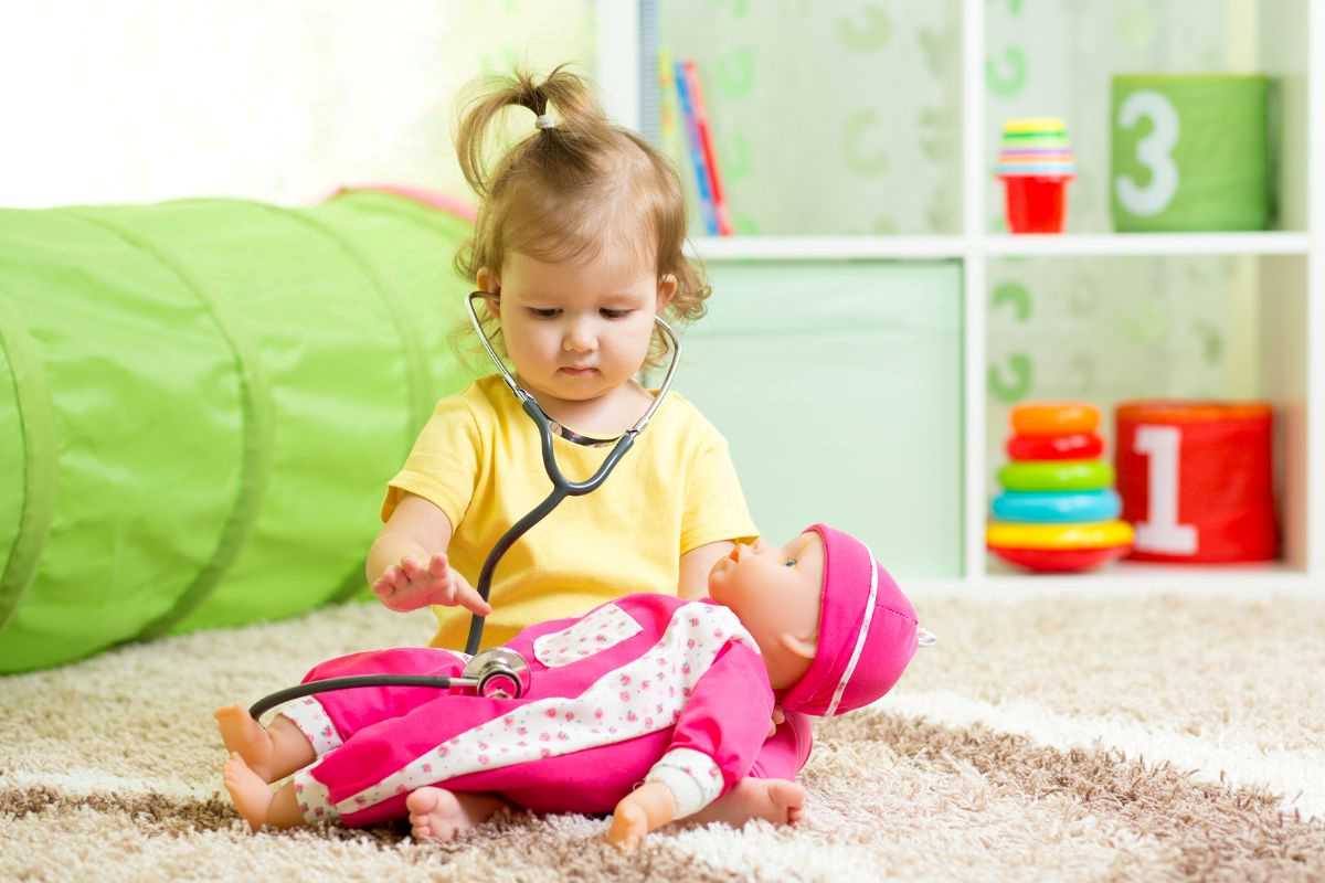 bambina che gioca con la bambola e lo stetoscopio