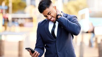 un uomo d'affari con il cellulare in mano si massaggia il collo dolorante
