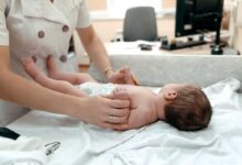 pediatra che visita neonato per individuare la malattia rara lipasi acida lisosomiale