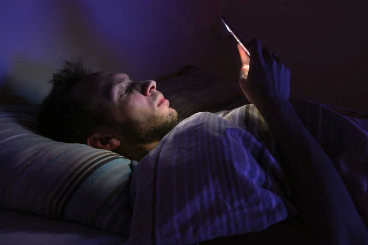 ragazzo che utilizza lo smartphone a letto