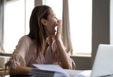 donna al lavoro che sbadiglia perché è in debito di sonno